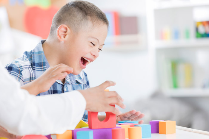 little boy smiling while playing with blocks