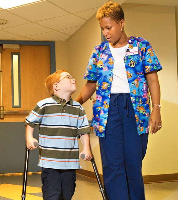 nurse walking with young disabled boy
